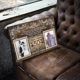 Personalized 50th anniversary canvas featuring photos and elegant floral details resting on a leather armchair.