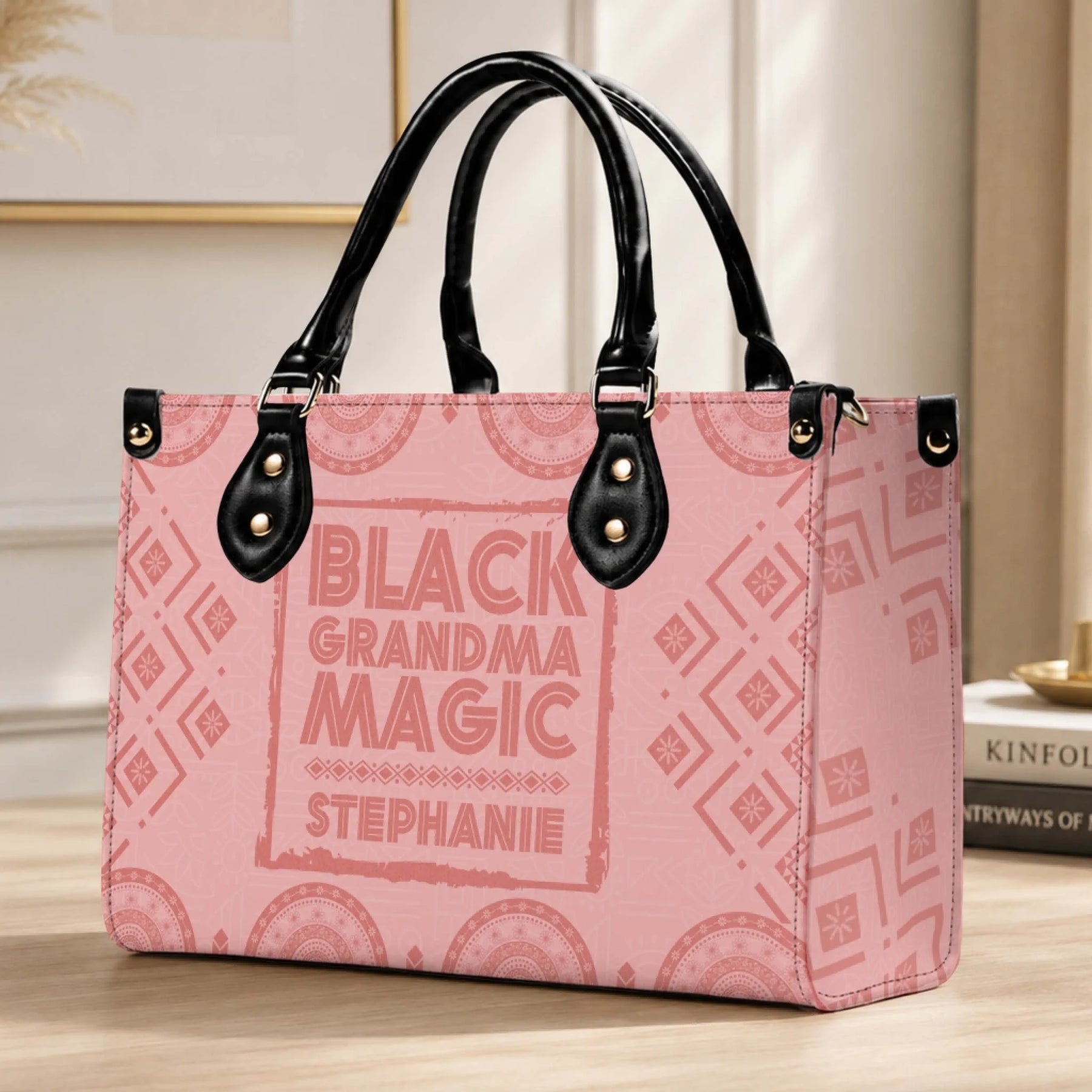 A custom Black Grandma Magic handbag with pink patterned fabric and black leather accents displayed on a wooden desk surface.