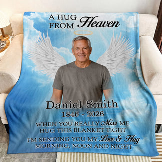Personalized memorial throw blanket with a custom photo and angel wings against a soft blue sky background.