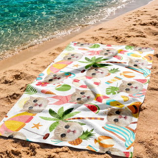 A soft custom photo beach towel featuring a cute cat face pattern surrounded by tropical summer icons on the sand.