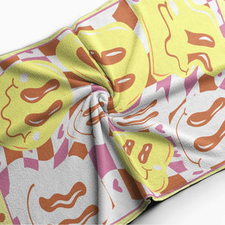 Close up of a personalized beach towel with a colorful checkerboard and wavy smiley face print labeled with Christina.