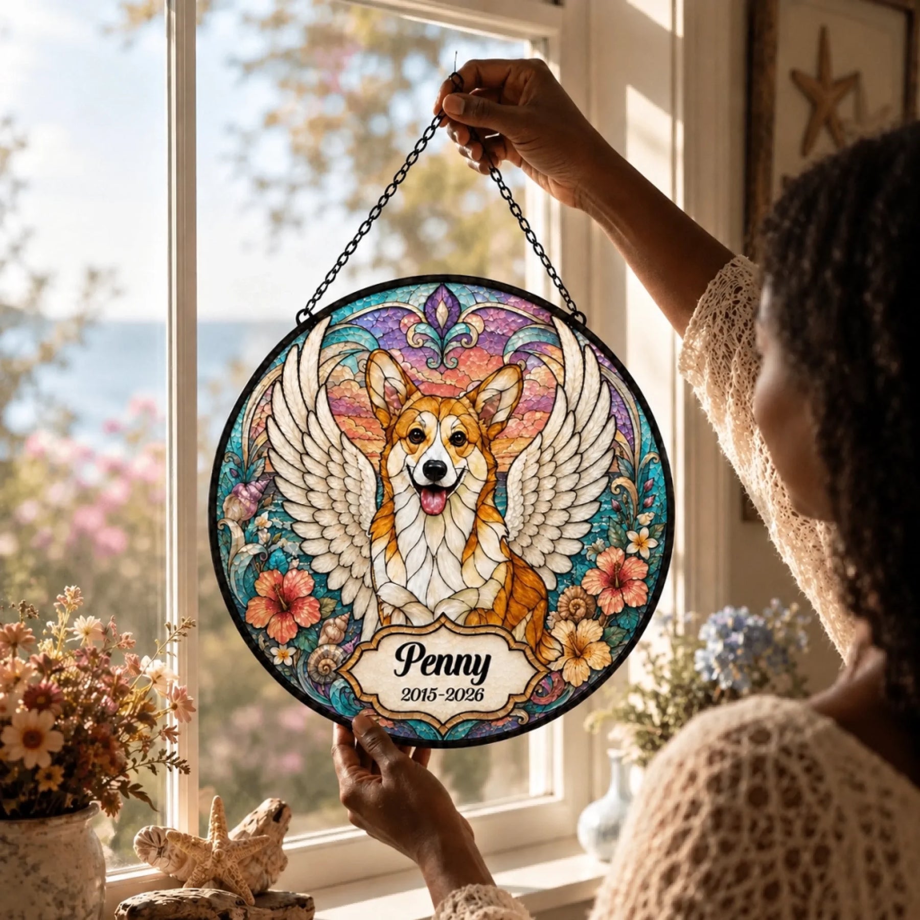 A woman holding a custom corgi memorial suncatcher with stained glass effect, angel wings, name, and dates of life.