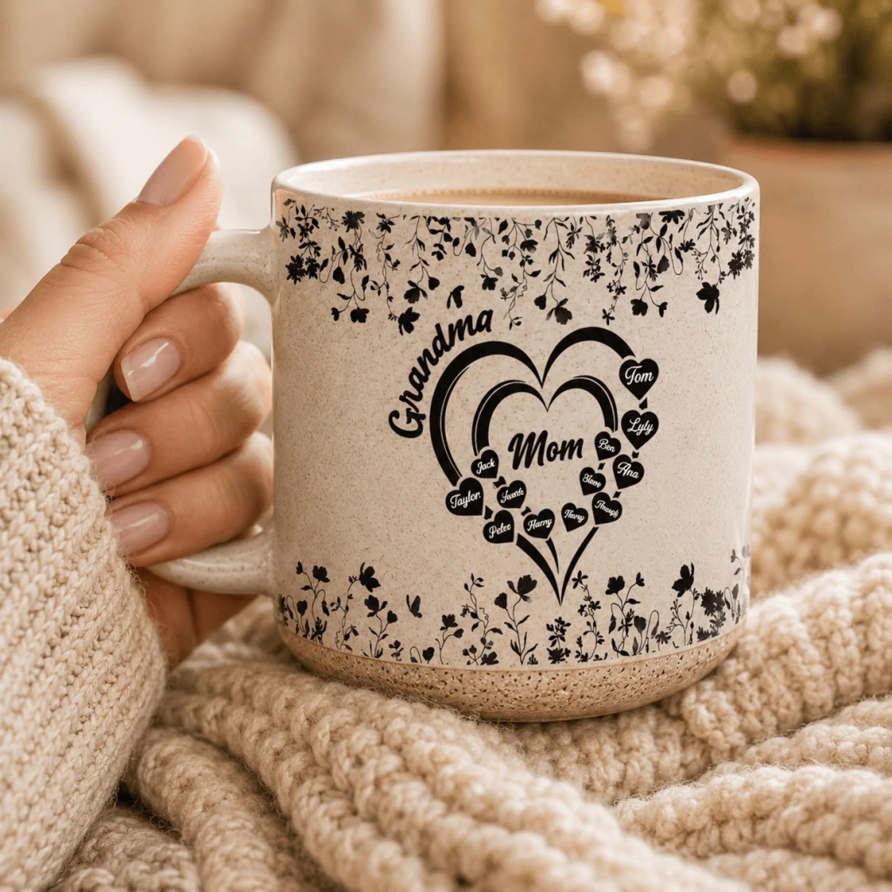 Hand holding a custom floral heart mug for Mom and Grandma with names displayed inside heart shapes for a family gift.