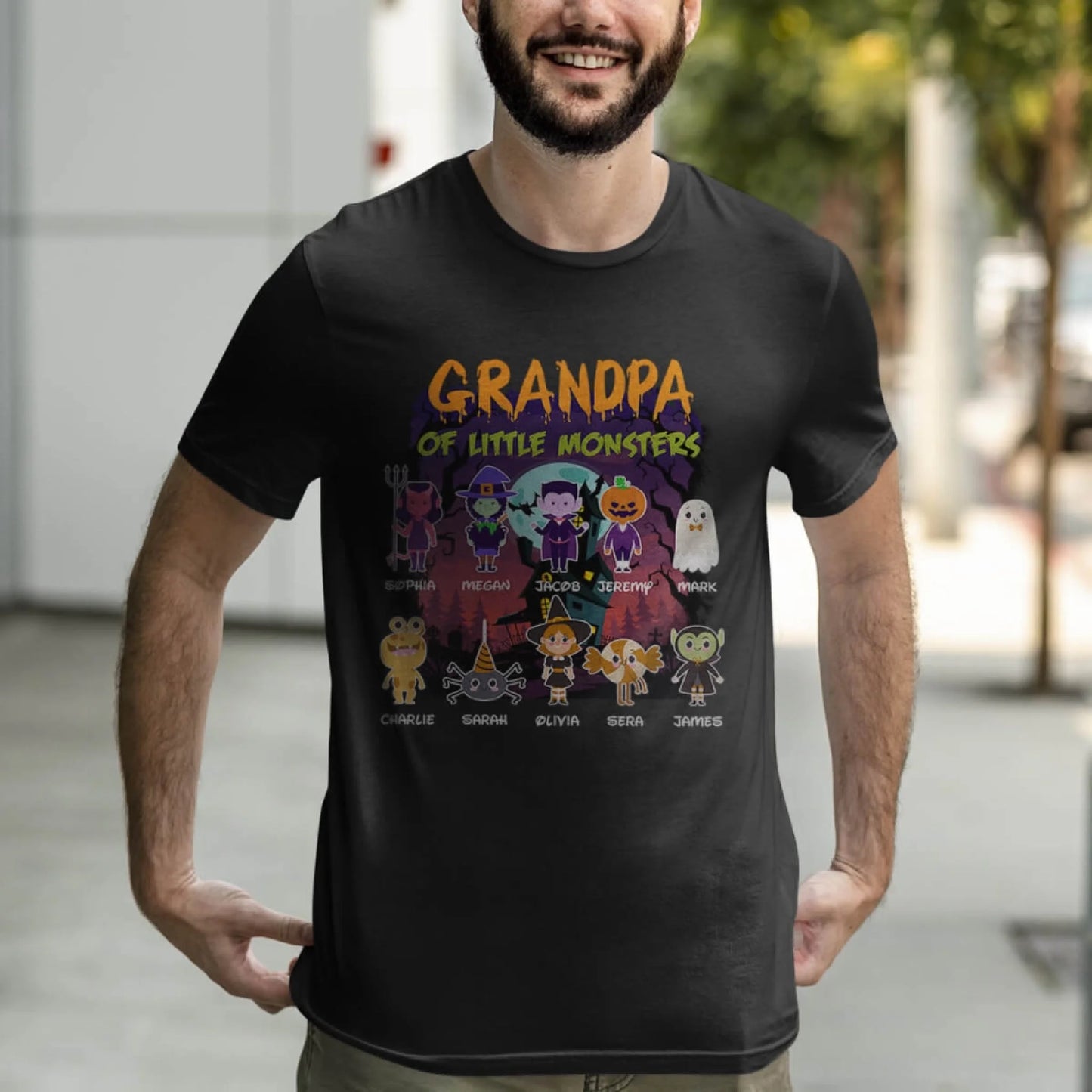 A man models a black personalized Halloween t-shirt with a Grandpa of Little Monsters design and family names.