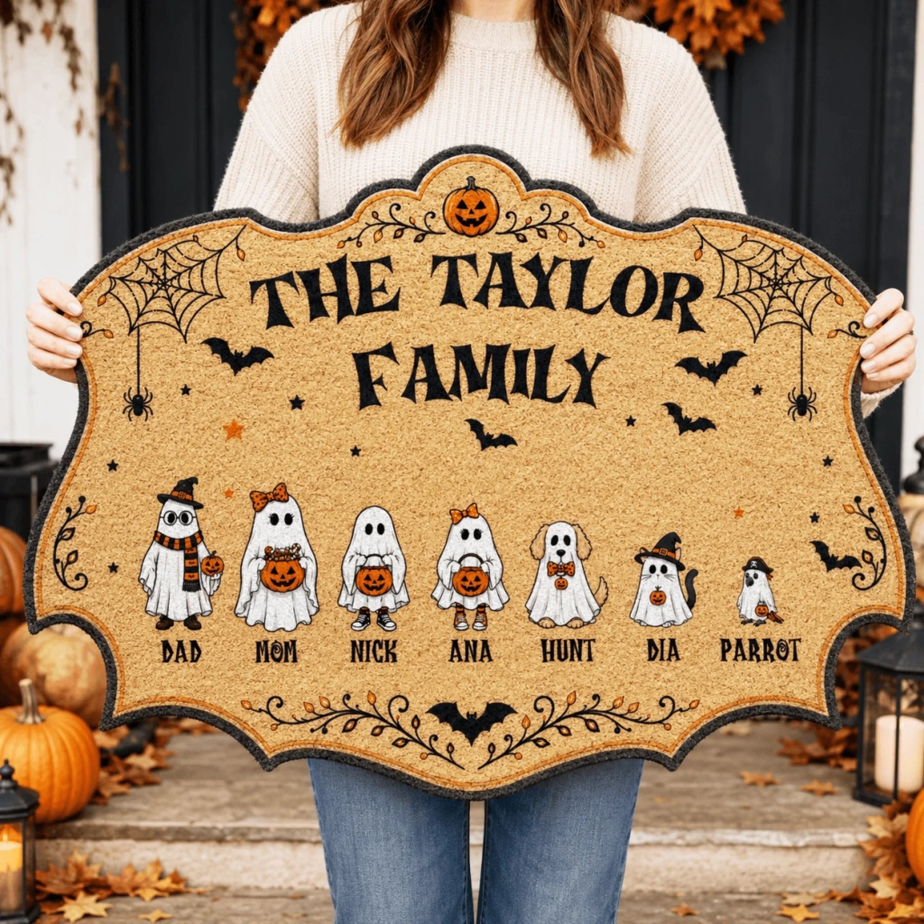 Person holding a custom Halloween doormat personalized with ghost characters of the Taylor family members and pets.