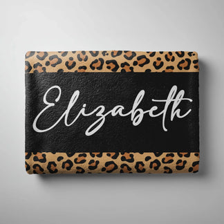 A folded personalized leopard print beach towel displaying the name Elizabeth printed in stylish white script font