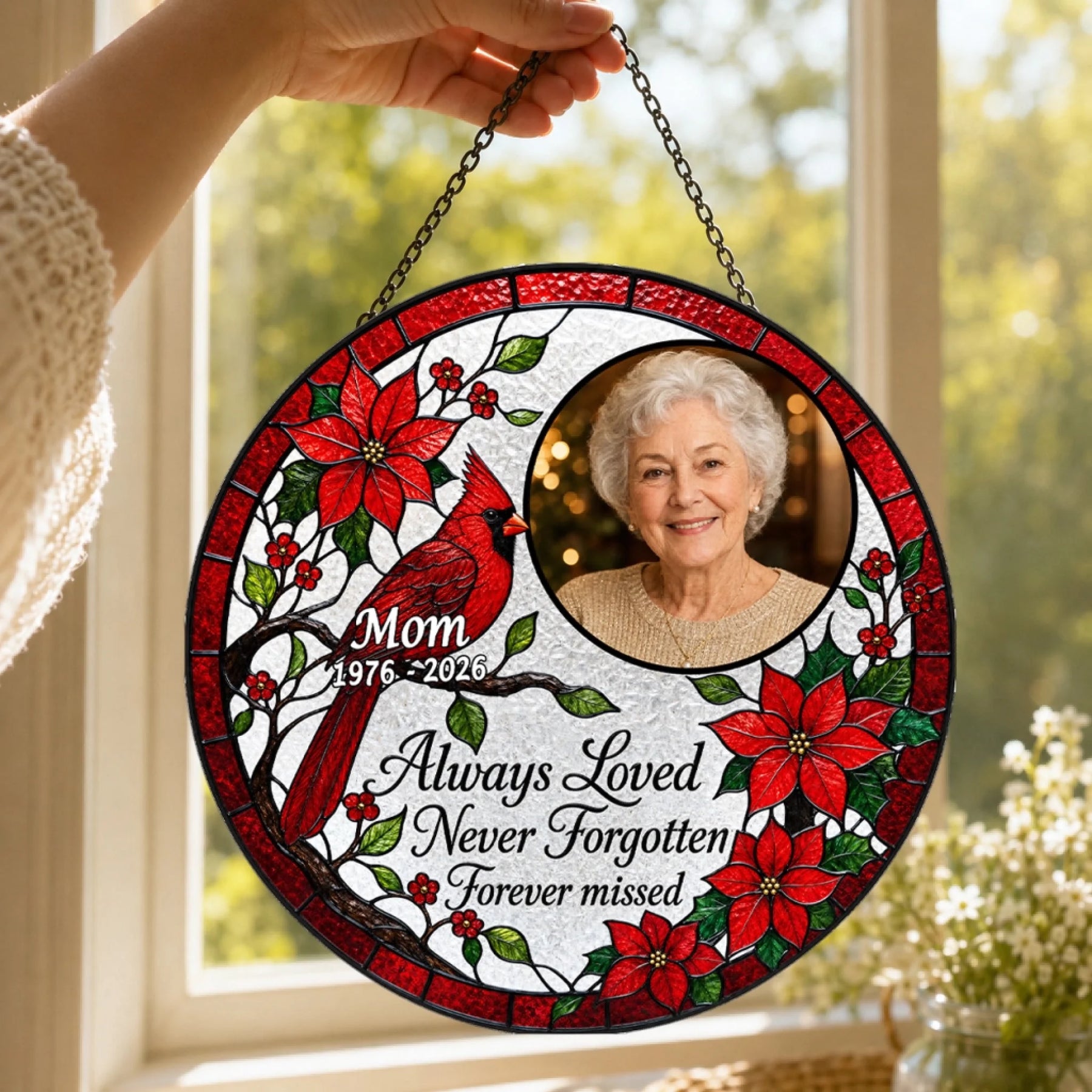 A woman holding a circular cardinal memorial suncatcher with a custom portrait and dates to honor a lost loved one