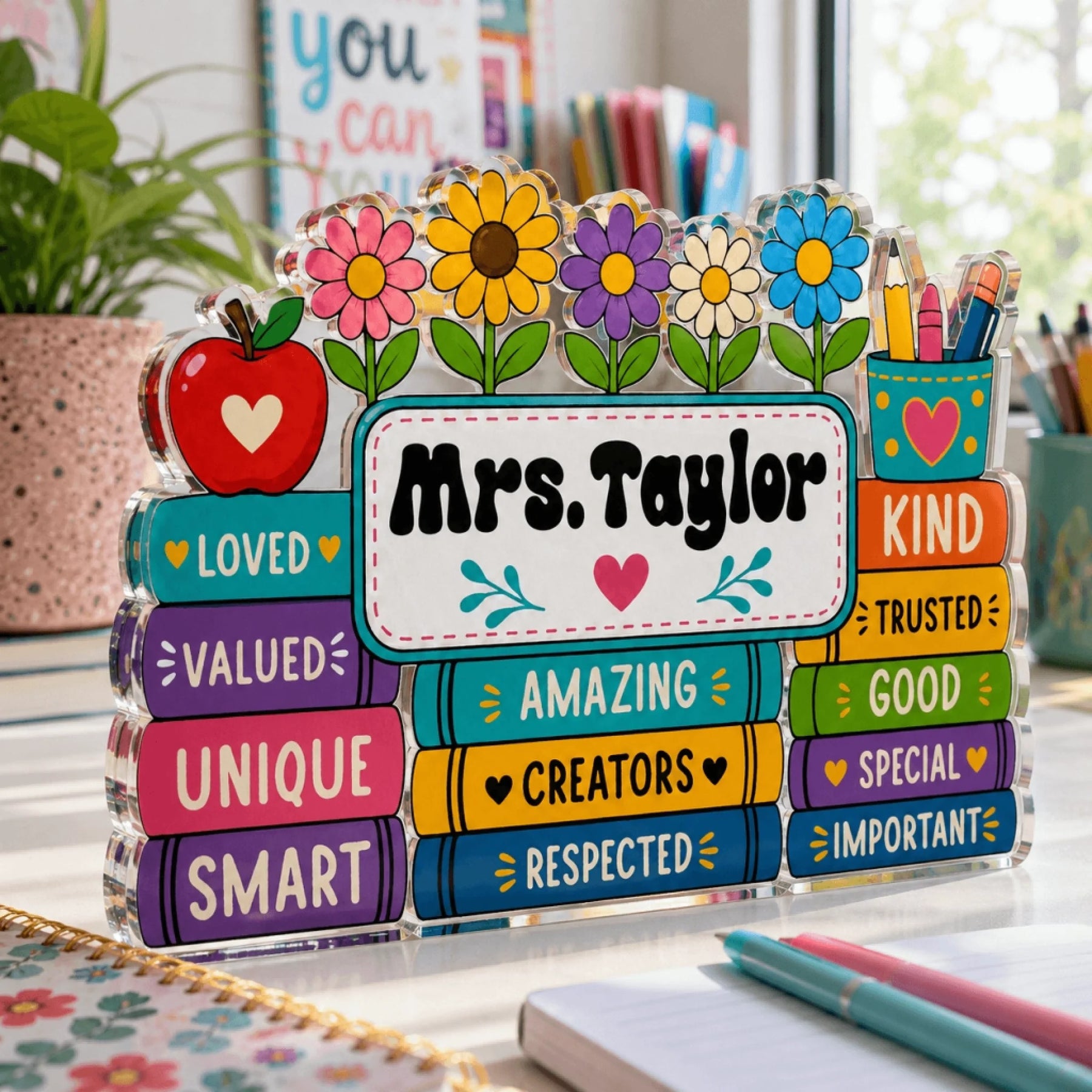 Acrylic teacher name plaque with colorful school theme, including books labeled with positive adjectives for teachers.