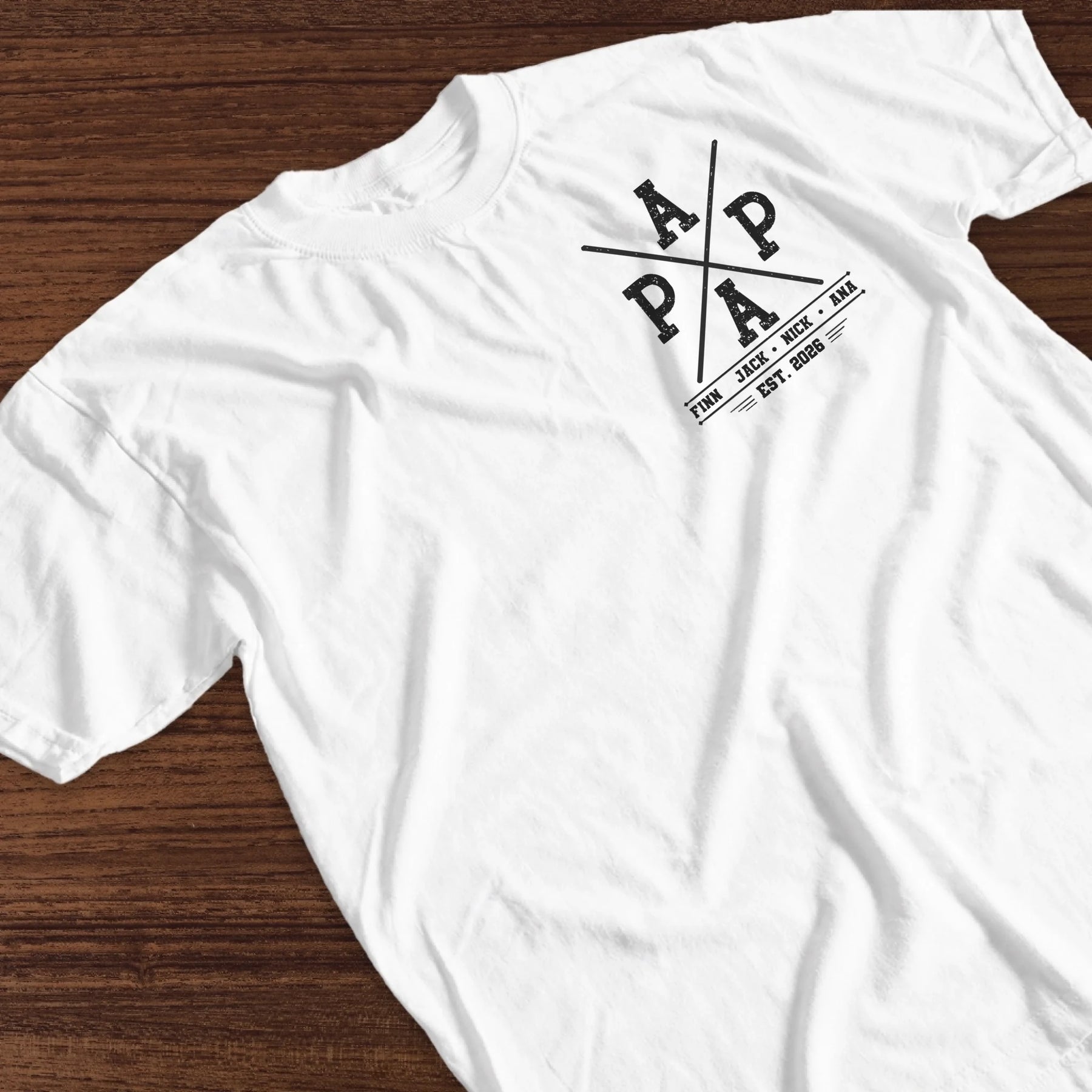 A close-up of a personalized white Papa fishing t-shirt with custom kids names and the established year 2026.