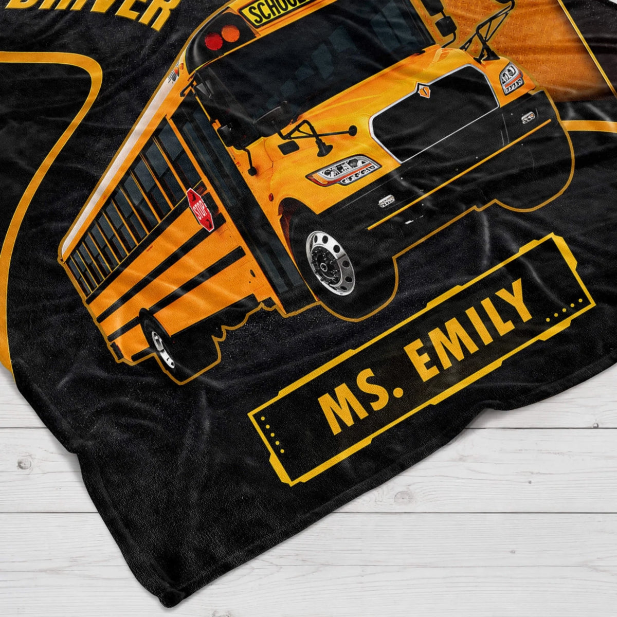 Close-up of a soft fleece blanket for bus drivers featuring a vibrant school bus graphic and custom name Ms. Emily.