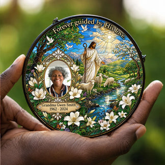 Personalized memorial suncatcher held in hand, featuring a custom photo, religious shepherd scene, and elegant lilies.