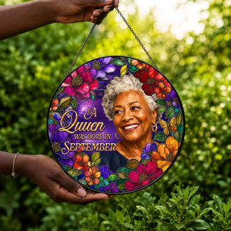 Elegant round stained glass suncatcher with floral theme and September queen text held against a nature background.