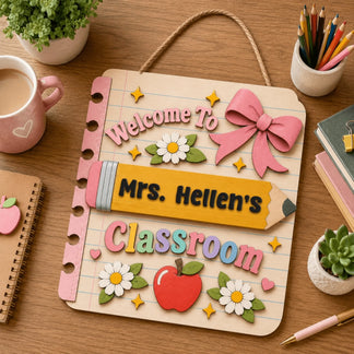 Decorative personalized wooden sign for teacher classroom featuring a pencil, apple, and flowers on a desktop setup.