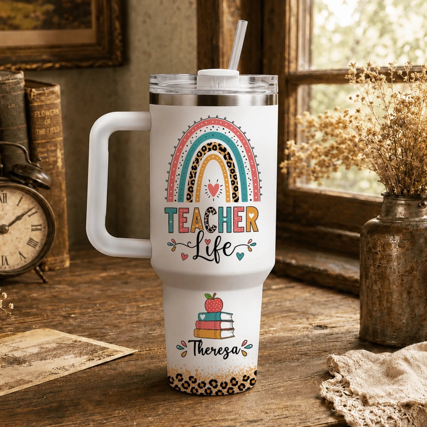 White personalized tumbler for teachers with a colorful rainbow design books and the custom name Theresa.