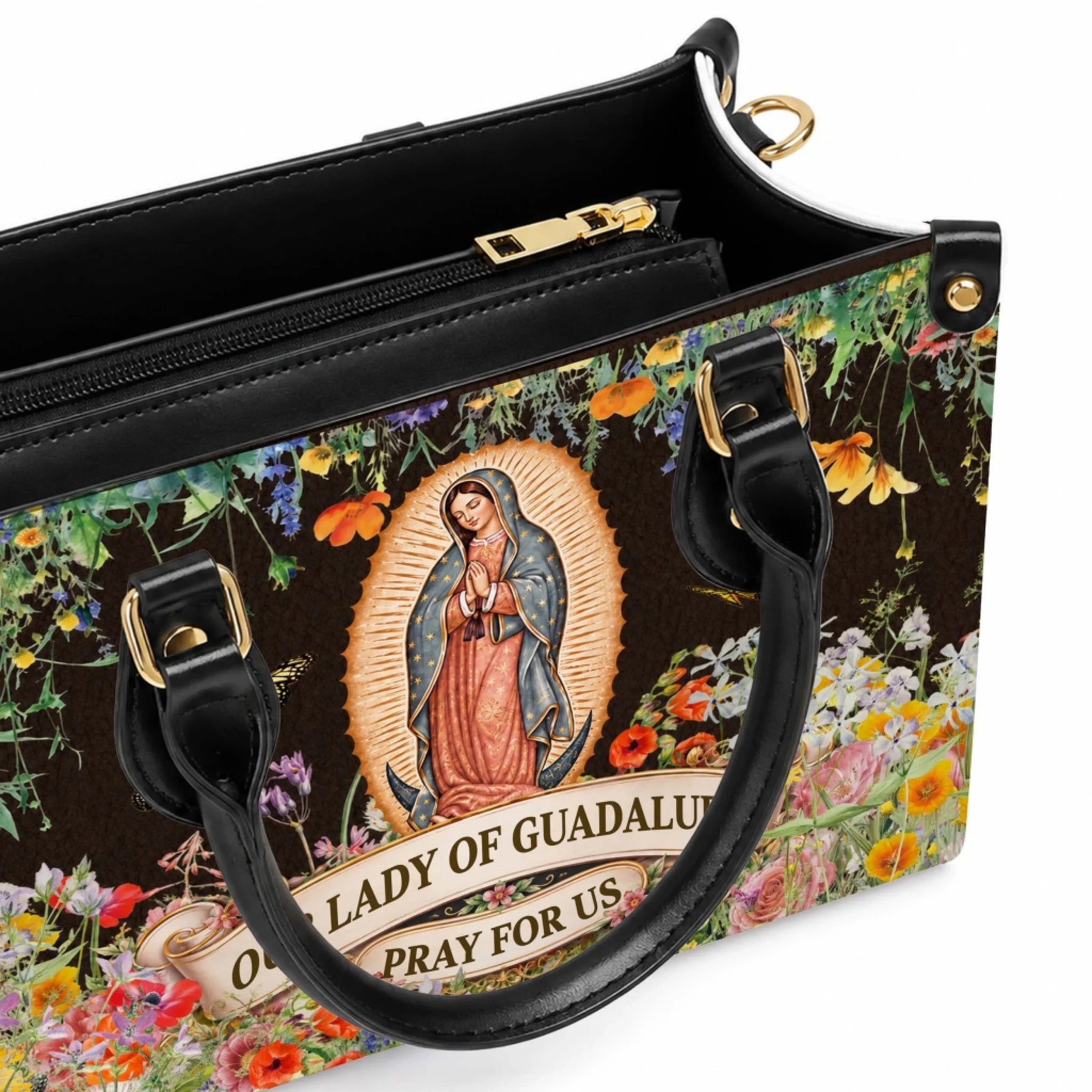 A close-up view of a stylish Our Lady of Guadalupe handbag featuring gold hardware, zipper closure, and floral art.