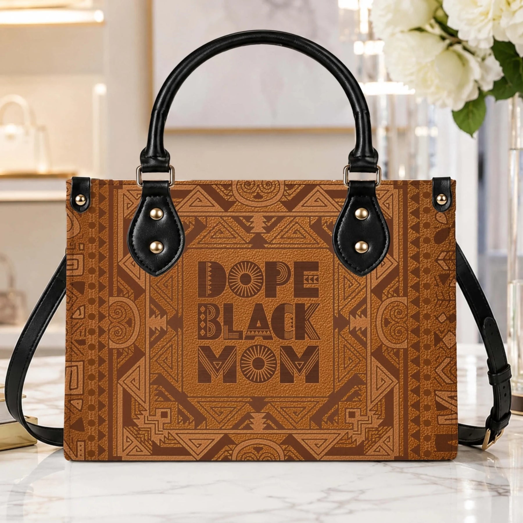 A close up of a brown leather handbag with geometric tribal prints and the inspirational text Dope Black Mom.