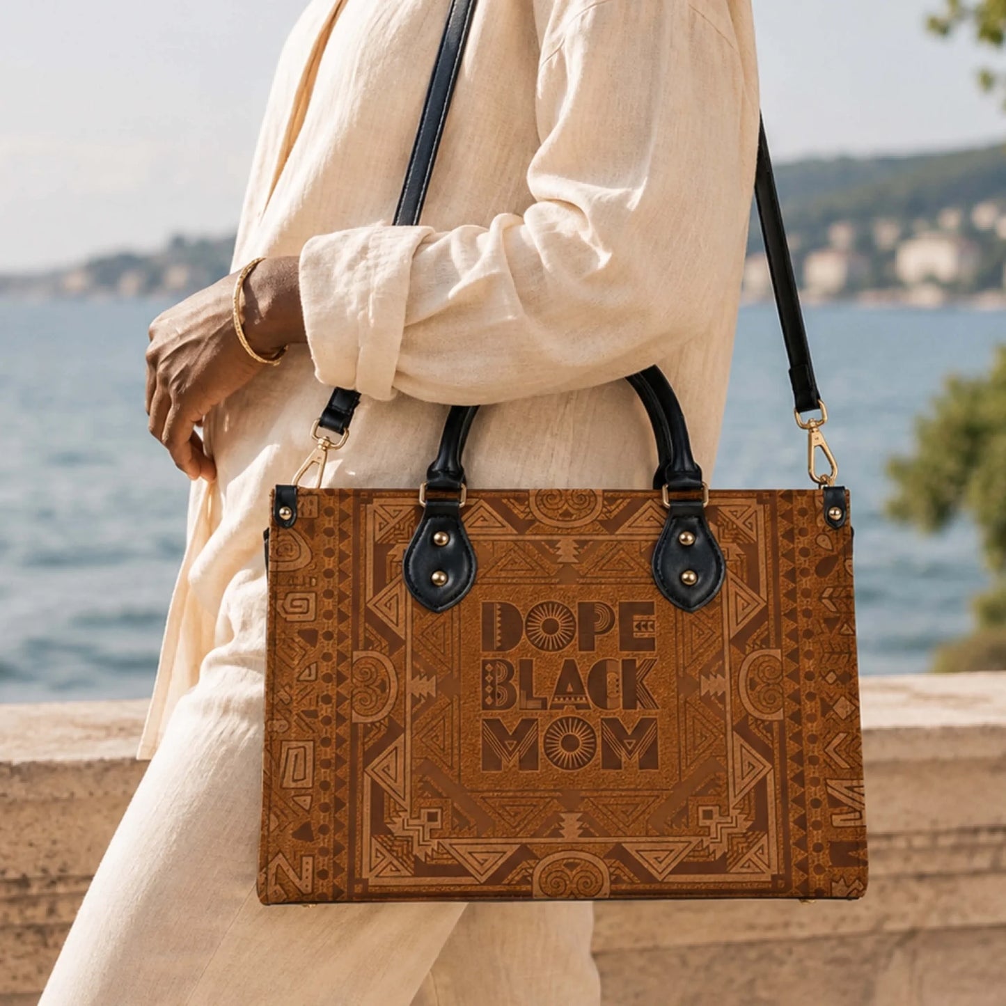 A person carrying a brown patterned handbag with Dope Black Mom text, ideal for a stylish and meaningful birthday gift.
