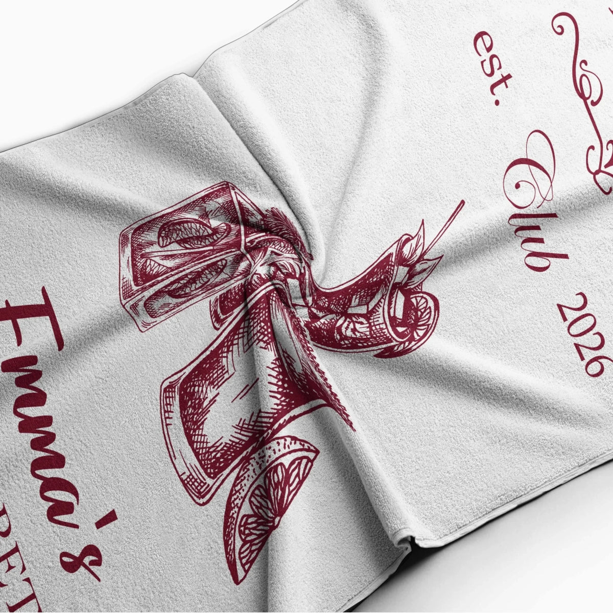 Close up view of a personalized bachelorette beach towel featuring cocktail art and custom party text details.