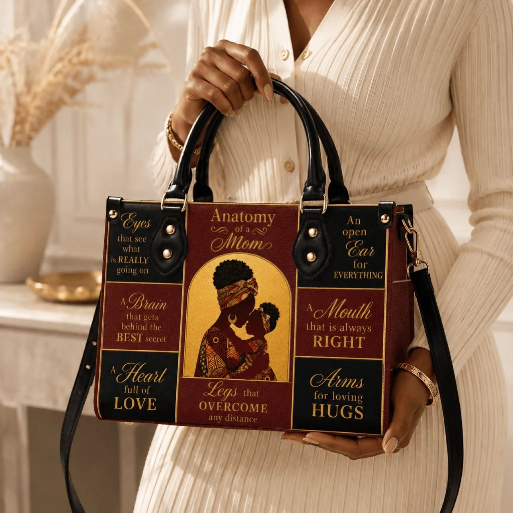 A woman holding a brown and black Anatomy of a Mom handbag with an elegant silhouette of a mother and child.