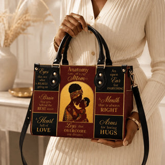 A woman holding a brown and black Anatomy of a Mom handbag with an elegant silhouette of a mother and child.