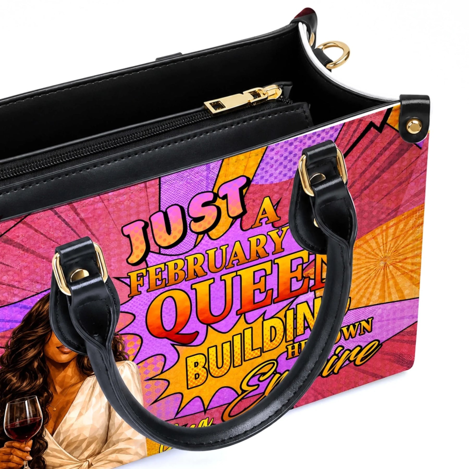 Close up of a personalized february queen empire handbag featuring high quality black handles and gold hardware.