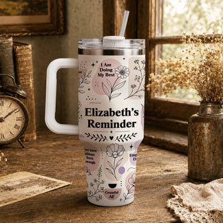 Floral tumbler with inspirational quotes on a rustic wooden desk with vintage books and a clock.