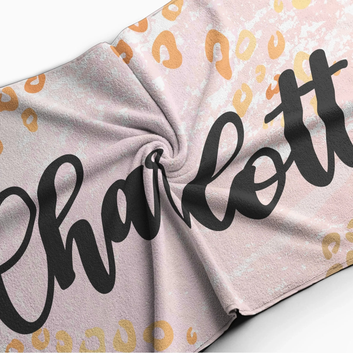 Folded custom beach towel with a trendy leopard print design and a name, showcasing the soft fabric texture.