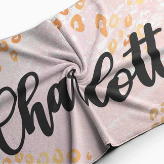 Folded custom beach towel with a trendy leopard print design and a name, showcasing the soft fabric texture.
