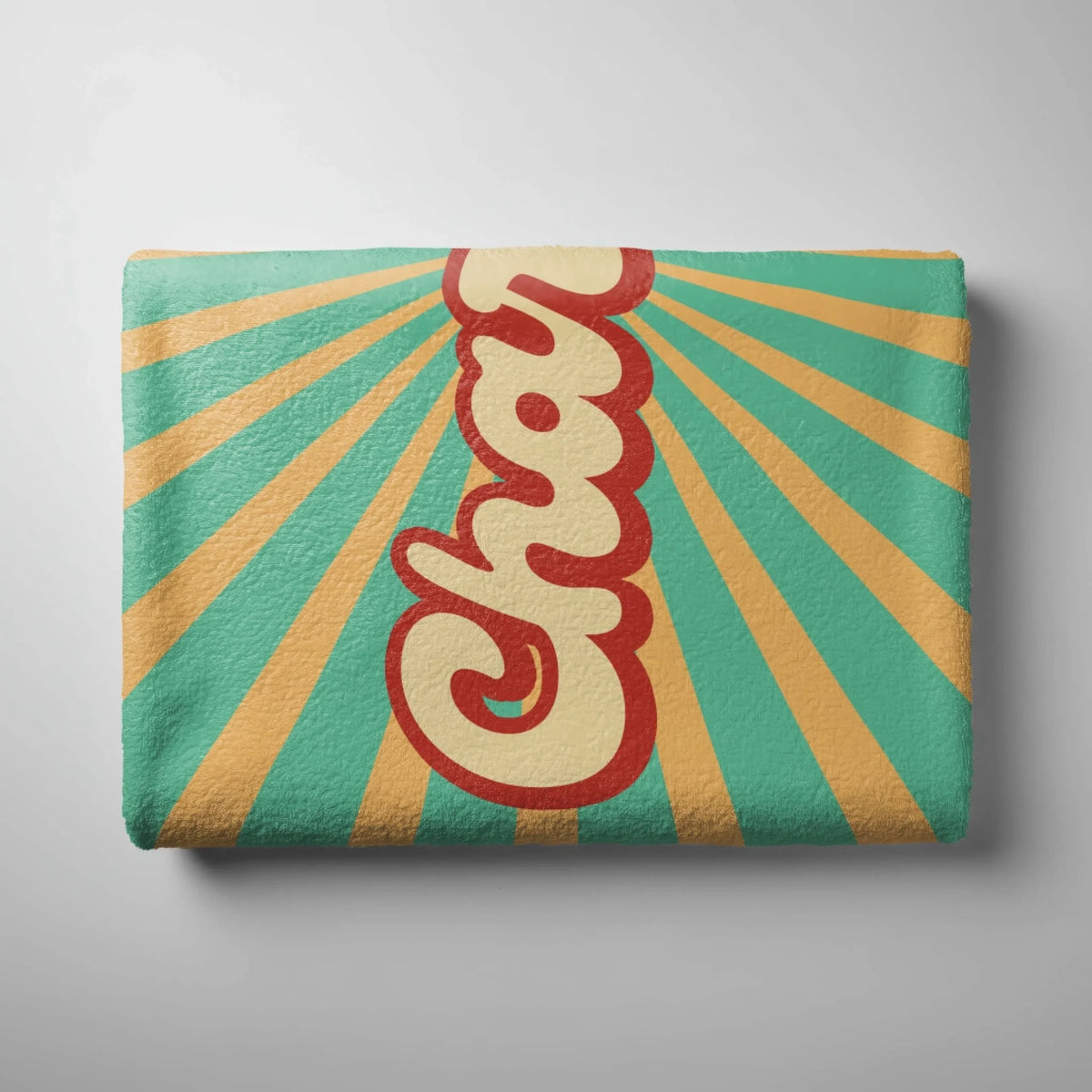A folded beach towel with a vintage sunburst design and custom Charlotte text in a bold red and yellow script.
