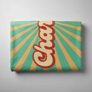 A folded beach towel with a vintage sunburst design and custom Charlotte text in a bold red and yellow script.