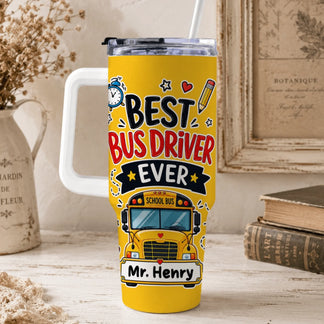 A yellow tumbler with a white handle and straw, featuring "BEST BUS DRIVER EVER", a school bus graphic, and "Mr. Henry" in a rustic setting.