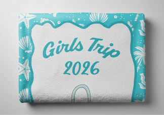 A folded personalized beach towel with a Girls Trip 2026 design and teal coastal pattern in a beach theme.