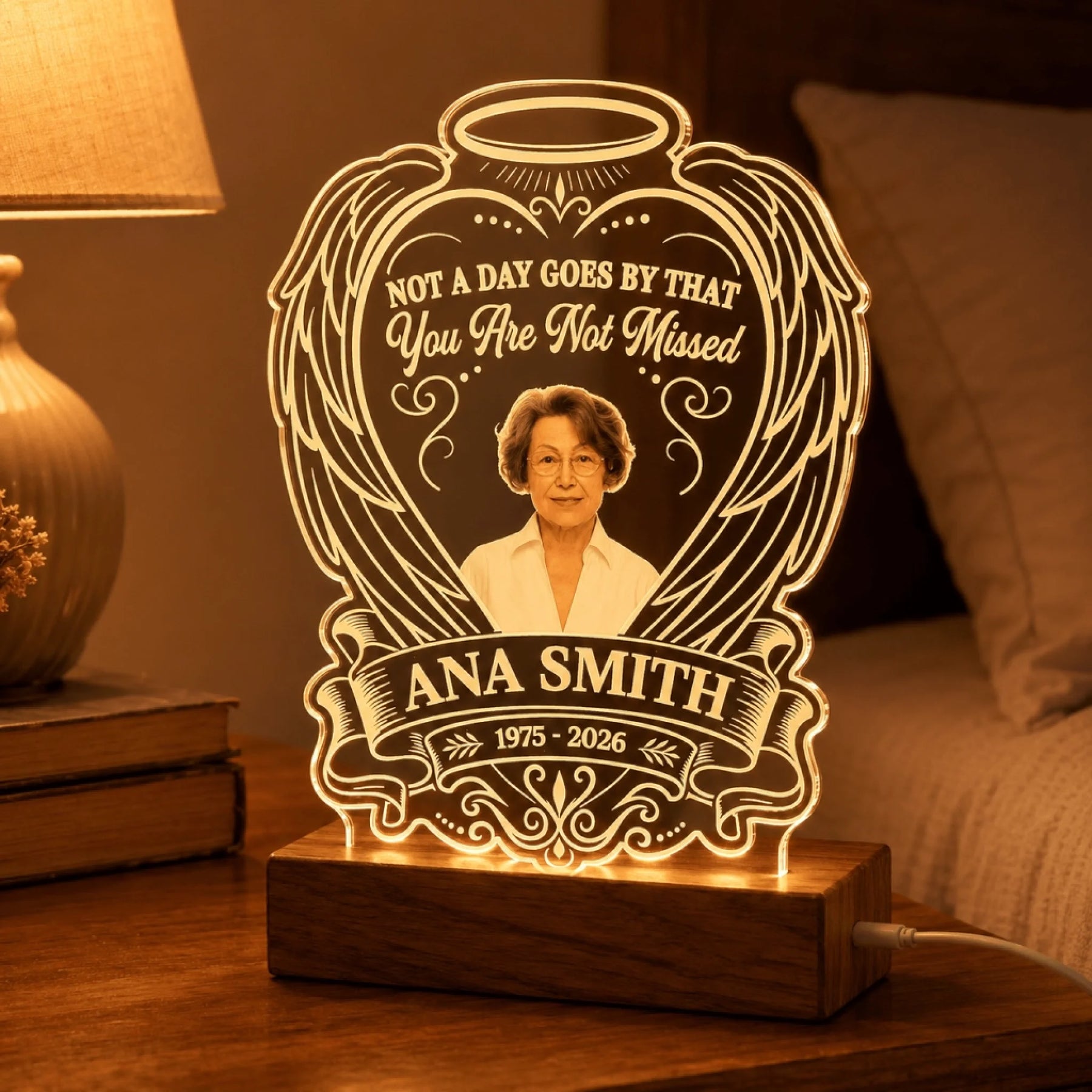 Glowing custom memorial night light with angel wing design and Ana Smith memorial text on a bedroom nightstand.