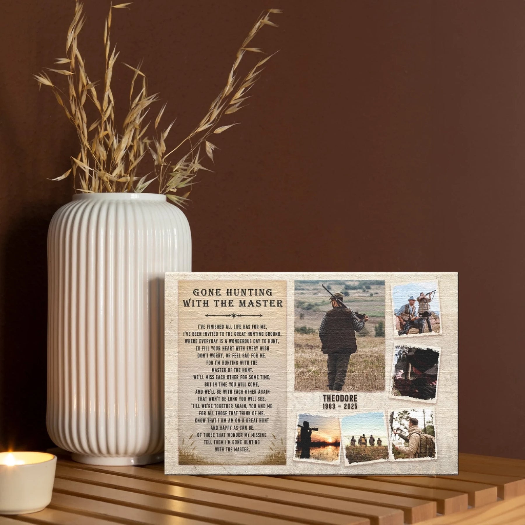 A canvas print featuring hunting photos and text, displayed on a wooden table next to a white vase with dried foliage and a candle.