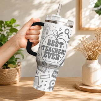 Hand holding a white personalized teacher tumbler featuring educational icons and Best Teacher Ever quote design.