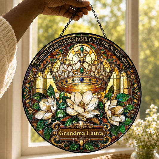 Person holding a round personalized Grandma Laura stained glass suncatcher with a royal crown and flower motif.