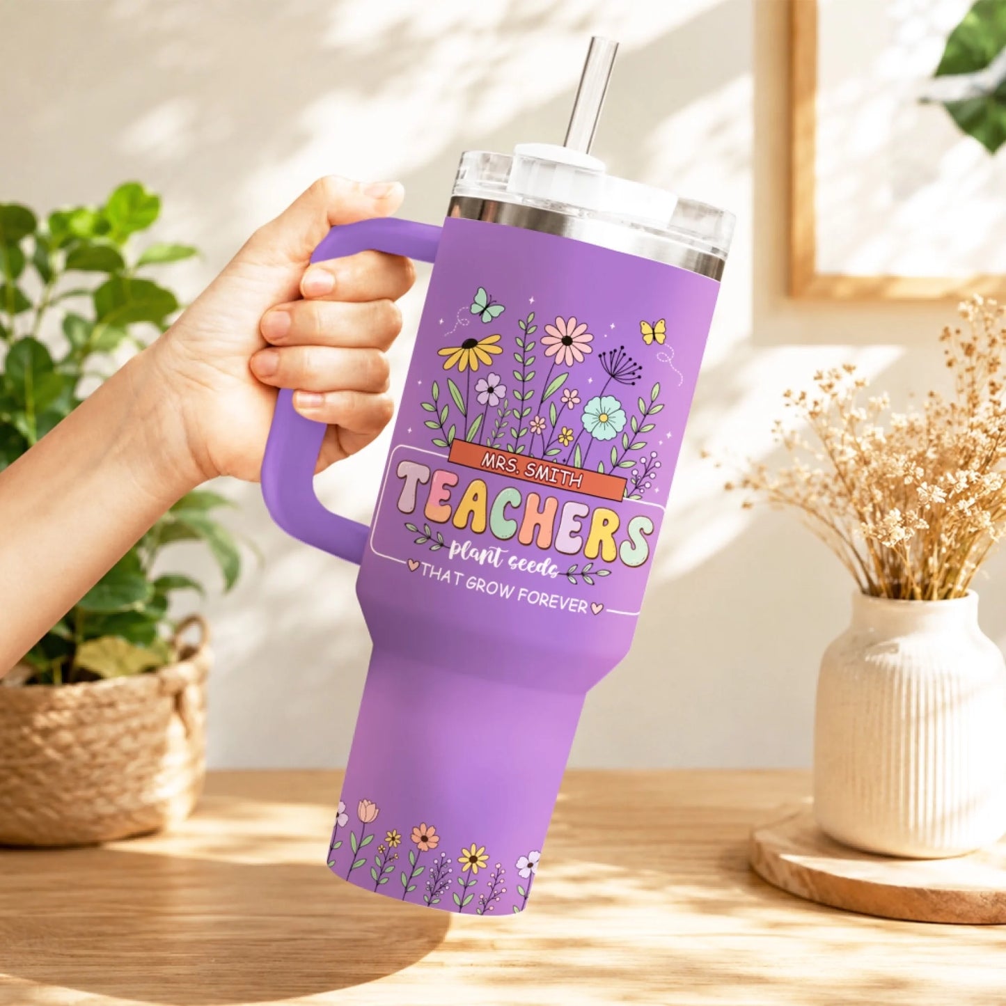 Woman holding a purple floral teacher appreciation tumbler with a handle, featuring a botanical design.