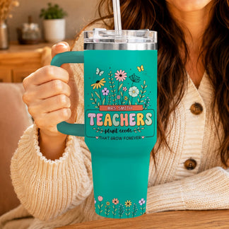 Woman holding a teal floral teacher appreciation tumbler with a straw and handle, indoor setting.