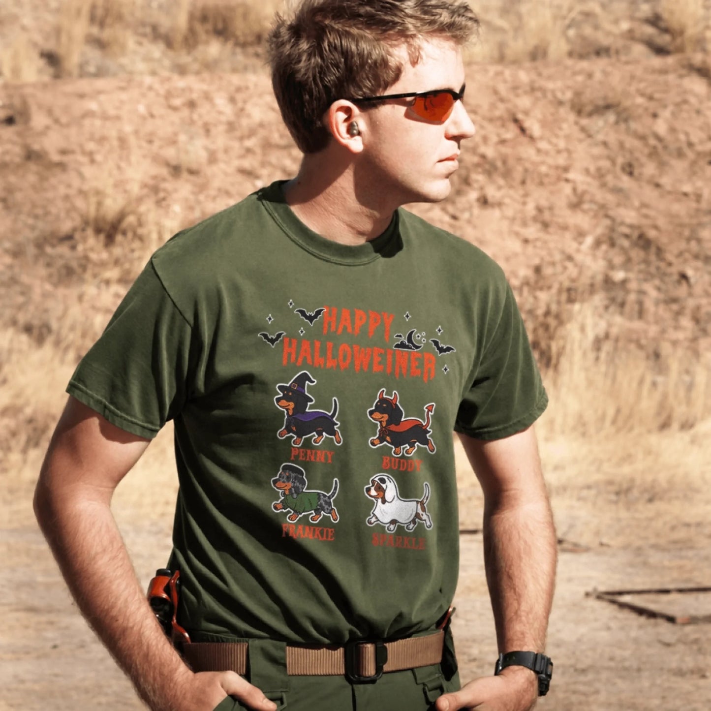 A man wearing an olive green Happy Halloweiner t-shirt featuring four personalized dachshund dogs in festive Halloween costumes.