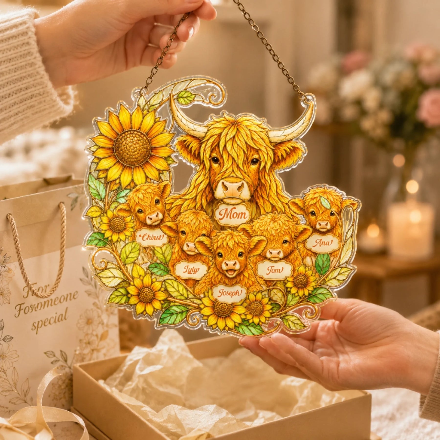 Decorative plaque with Highland cows and sunflowers held by two hands, with a gift box and floral background.