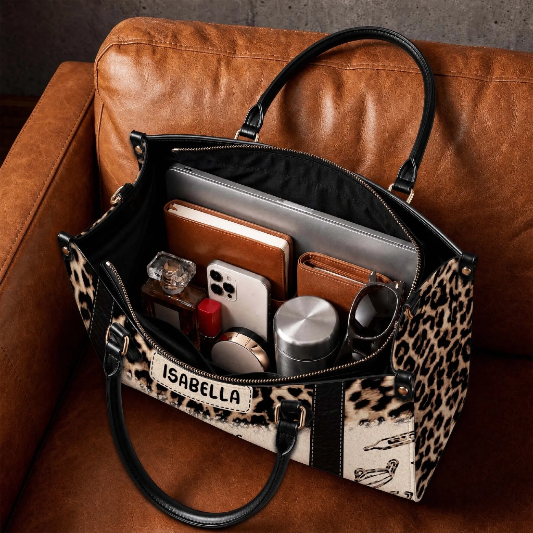 The interior of a personalized leopard print nurse bag filled with everyday essentials like a laptop notebook phone and accessories.