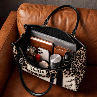 The interior of a personalized leopard print nurse bag filled with everyday essentials like a laptop notebook phone and accessories.