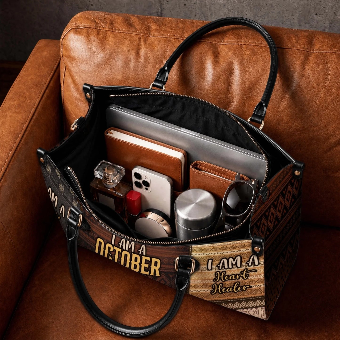 An open personalized tote bag showing interior storage space filled with a laptop, notebook, phone, and daily items.