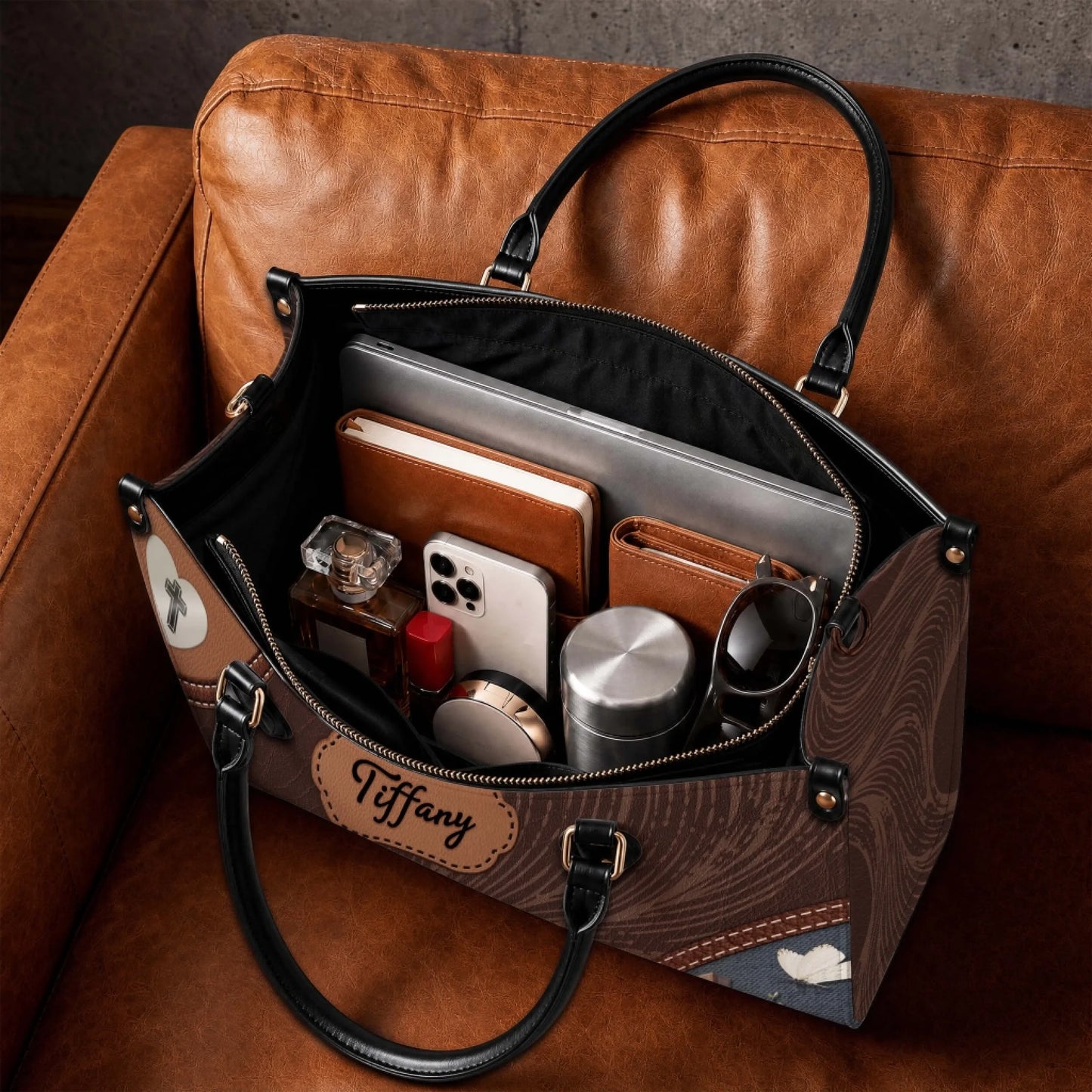 A spacious personalized leather tote bag filled with a laptop, notebook, phone, water bottle, and daily essentials.