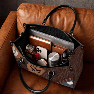 A spacious personalized leather tote bag filled with a laptop, notebook, phone, water bottle, and daily essentials.
