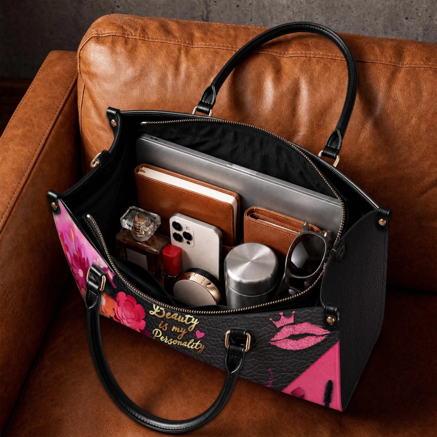 Spacious interior of a stylish personalized handbag filled with daily essentials including a laptop, notebook, and cosmetic items.