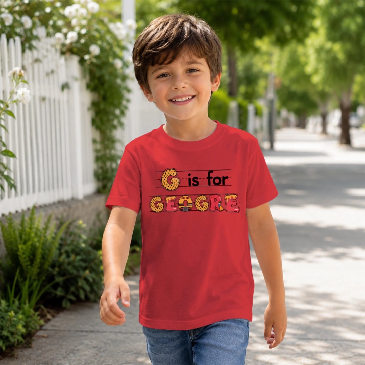 A boy in a red personalized back to school t-shirt with the custom name Geogre displayed in themed letter art.