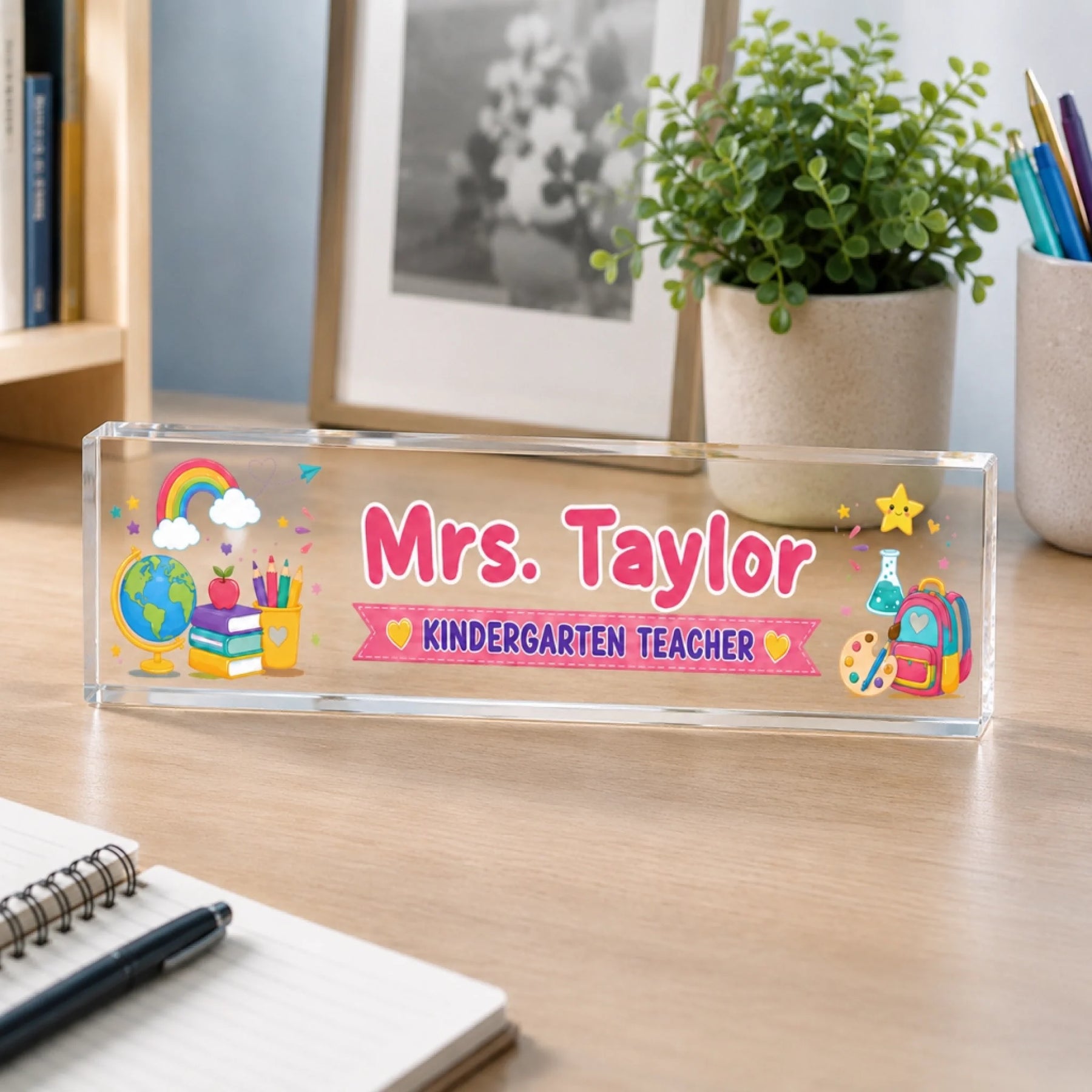 Personalized acrylic desk plaque for teachers featuring school supplies and the name Mrs Taylor on a wood desk.