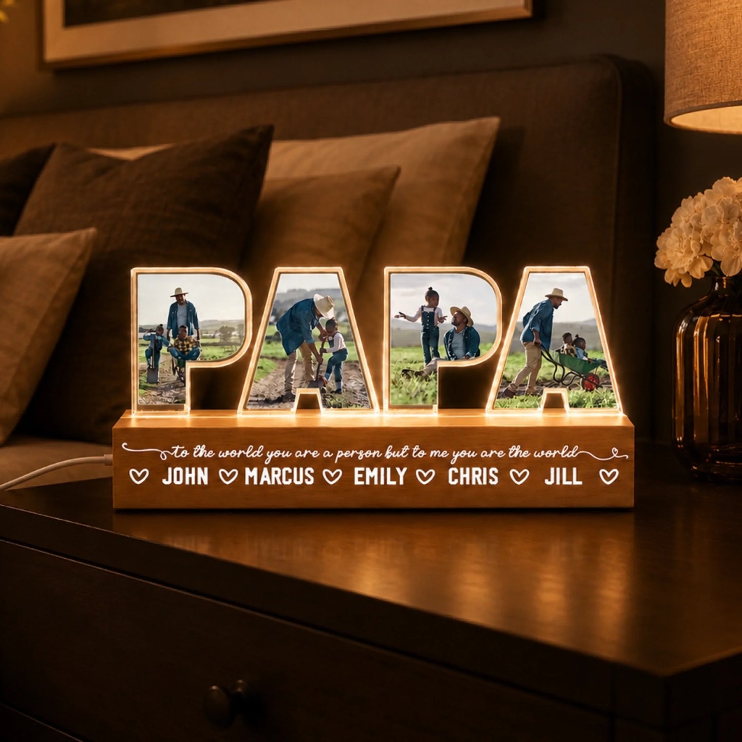 Personalized 'DAD' light box with family photos on a wooden surface.