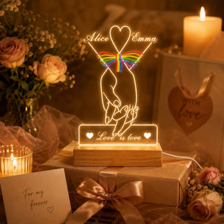 Decorative LED lamp with 'Alice & Emma' and rainbow heart design, surrounded by flowers and candles.